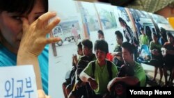 5일 한국 서울 외교부 청사 앞에서 시위를 벌이던 탈북민 고미화씨가 라오스에서 강제 북송된 청소년들의 사진을 든 채 눈물을 흘리고 있다.
