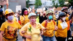 Norma Lewis holds a flower while forming a "wall of moms" during a Black Lives Matter protest in Portland, Ore, July 20, 2020. 