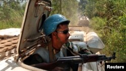 Des Casques bleus patrouillant à bord des véhicules blindés près du village abandonné de Kaswara, en Ituri, RDC, 14 juillet 2006. 