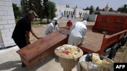 Des employés de la municipalité tunisienne chargent le corps d'une victime du COVID-19 dans un camion à l'hôpital Ibn al-Jazzar de la ville de Kairouan, dans le centre-est, le 4 juillet 2021.