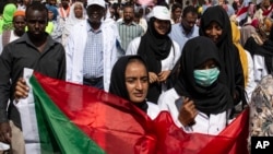 A protester carries a Sudanese flag as they chant against military rule and demand the prosecution of former officials, at the Armed Forces Square, in Khartoum, Sudan, April 28, 2019. 