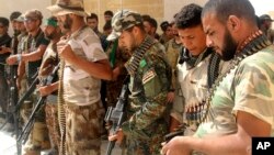 Newly arrived Iraqi Shi'ite militiamen check their weapons in the predominately Sunni city of Nukhayb, in southwest Iraq, May 21, 2015. Many analysts predict deep sectarian divisions will cripple the fight against the Islamic State group.