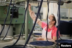 FILE - A worker checks a machine that arranges thick yarn at a factory owned by Hong Kong's Novetex Textiles Limited in Zhuhai City, Guangdong province, China, Dec. 13, 2016. A new Novetex spinning mill, the first to open in Hong Kong in half a century, aims to reuse waste, harnessing pioneering recycling technology to try to make the fashion industry more sustainable.