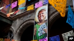 FILE - A banner with an image of Donald Trump promotes an exhibition that features dozens of works by Mexican and international cartoonists, mocking among other things the U.S. president's derogatory statements about Mexicans and his plans to build a wall and make Mexico pay for it.