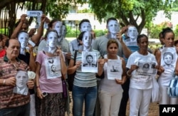 Cuban dissidents pose wearing masks depicting US President Barack Obama and holding pictures of imprisoned dissidents as they protest against the reopening of the US embassy in the island, Aug. 9, 2015.