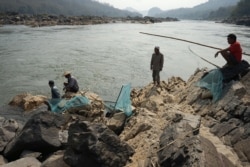 Fishermen lay their nets on the Mekong River near Luang Prabang close to the site of an approved Laos dam site, Feb. 8, 2020.