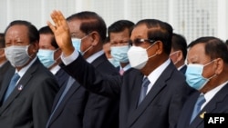 រូបឯកសារ៖ ​លោក​នាយករដ្ឋមន្ត្រី ហ៊ុន សែន (លើក​ដៃឡើង) ឈរ​ជាមួយ​នឹង​មន្ត្រី​កំពូលៗ​របស់​លោក​មួយ​ចំនួន​រួម​មាន​លោកលោក ទៀ បាញ់ និង​លោក ស ខេង ក្នុង​អំឡុងពេល​ជូន​ដំណើរ​ព្រះមហាក្សត្រ​យាង​ចេញ​ដំណើរ​ទៅ​កាន់ប្រទេស​ចិនកាល​ពី​ថ្ងៃទី៦ ខែតុលា ឆ្នាំ២០២០។