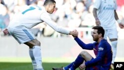 Cristiano Ronaldo, joueur du Real Madrid, à gauche, aide le Barcelonais Lionel Messi à se remettre sur pied lors du match de football de la Liga espagnole à Madrid, le 23 décembre 2017.