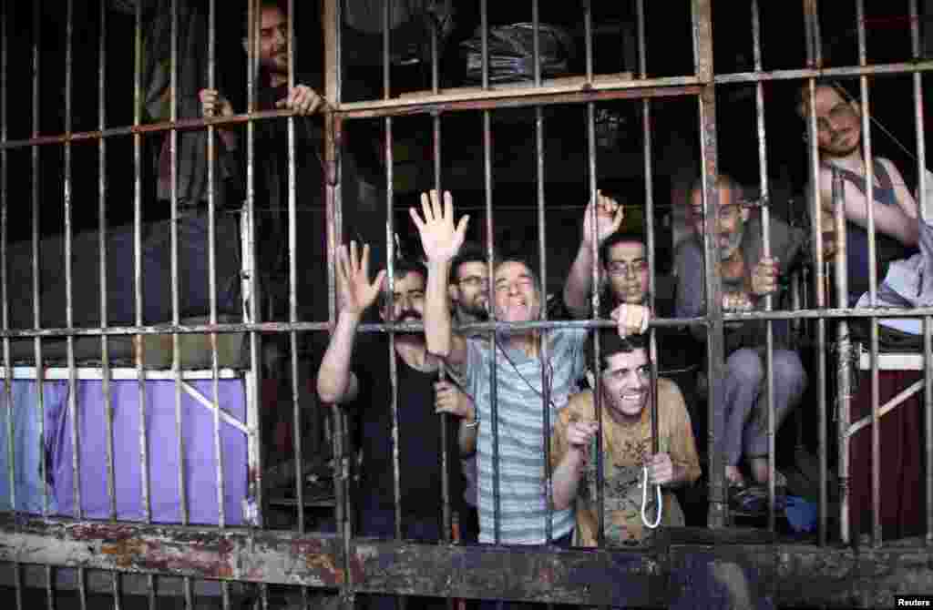 Inmates gesture from behind bars in Aleppo&#39;s main prison, May 22, 2014.