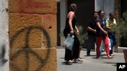 Orang-orang melintasi jalan Ledra, sebuah titik perlintasan yang membentang dari utara ke selatan antara zona penyangga PBB di ibukota Siprus, Nicosia, yang terbagi dua, 28 Juni 2017 (foto: AP Photo/Petros Karadjias)