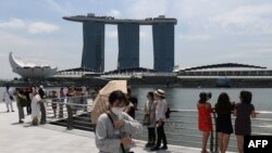 A visitor, wearing a protective facemask amid fears about the spread of the COVID-19 novel coronavirus, walks along Merlion Park in Singapore on February 17, 2020. (Photo by Roslan RAHMAN / AFP)