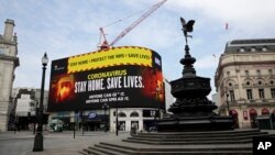 Layar video menampilkan pesan untuk masyarakat agar tetap tinggal di rumah untuk menghambat penyebaran virus corona, di Piccadilly Circus, London, 8 April 2020. 