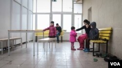 A family wait their turn to make a legal crossing at one of the official camps by the Serbia/Hungary border. Hungary now only allows 10 refugees and migrants to cross a day. (VOA /J. Owens)