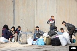 FILE - Rebel fighters and their families are seen upon their arrival in the Qalaat al-Madiq village in the province of Hama after being evacuated from the Qadam neighborhood on the outskirts of Damascus, March 13, 2018.