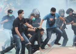 Polisi menahan para demonstran di tengah asap gas air mata dalam aksi yang berakhir rusuh di Jakarta, Kamis (8/10).
