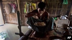 FILE - A boy eats rice inside his house in India, which is partially submerged in floodwater, Sept. 2, 2015.