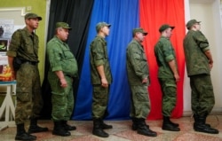 Militan Republik Rakyat Donetsk yang memproklamirkan diri, antre di pusat informasi untuk memberikan suara dalam pemilihan parlemen Rusia melalui sistem online di kota Donetsk yang dikuasai pemberontak, Ukraina 17 September 2021. (REUTERS/Alexander Ermochenko)