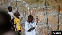 Internally displaced boys stand next to barbed wire inside a United Nation Mission in South Sudan (UNMISS) compound in Juba, Dec. 19, 2013. U.N. officials say many children have been separated from their families since fighting broke out on Dec. 16, and are particularly vulnerable.