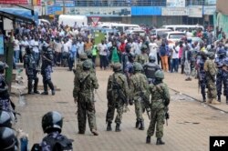 Ugandan soldiers stand in front of a crowd during protests by supporters of Ugandan pop star-turned-lawmaker Bobi Wine, in Kampala, Uganda, Aug. 31, 2018.