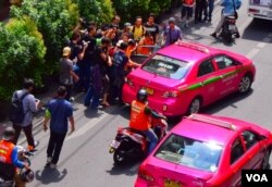 A woman being forced into a taxi by suspected plainclothes police officers after she allegedly flashed a three-fingered salute signalling her opposition to the military coup in Bangkok, Thailand, June 1, 2014. (Steve Herman/VOA)