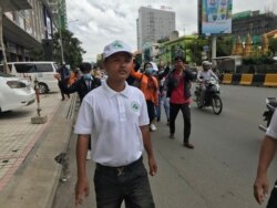 លោក ​ជុំ ហួត​ ដើរ​នៅពីមុខក្រុមអ្នកតវ៉ាសុំ​ឲ្យដោះលែង​លោក​ រ៉ុង ឈុន​ ទីក្រុងភ្នំពេញ ថ្ងៃទី​៣​ ខែ​សីហា​ ឆ្នាំ​២០២០។ (ហ៊ុល​ រស្មី/វីអូអេ)​