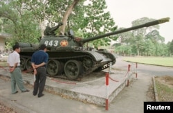 FILE - Tourists in Ho Chi Minh City look at Soviet-made tank number 843, made famous and preserved in situ since crashing through the gates of the former South Vietnamese presidential palace at the end of the Vietnam War in April 1975, Feb. 24, 2001.