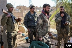 Fighters with the U.S.-backed Syrian Democratic Forces (SDF) check a makeshift camp for Islamic State (IS) group members and their families in the town of Baghuz, eastern Syria, March 9, 2019.