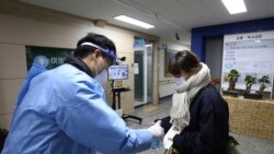 A teacher gives a hand sanitizer to a South Korean student before the College Scholastic Ability Test at a high school in Seoul Thursday, Nov. 18, 2021