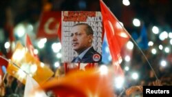 People wave flags and hold a portrait of Turkish President Recep Tayyip Erdogan as they celebrate the ruling AK Party's election win, in Ankara, Turkey Nov. 2, 2015.