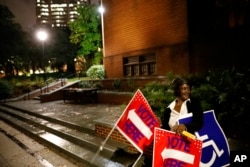 Poll worker Sarah Thomas places signs outside a precinct before polls open on election day in Atlanta, Nov. 6, 2018.