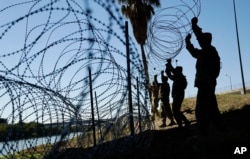 Members of the U.S. military install multiple tiers of concertina wire along the banks of the Rio Grande near the Juarez-Lincoln Bridge at the U.S.-Mexico border, Nov. 16, 2018, in Laredo, Texas.