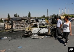 Turkish citizens walk past burnt and destroyed police and civilian vehicles near the presidential palace, in Ankara, Turkey, July 17, 2016, that were attacked by a Turkish airstrike during a military coup late Friday.