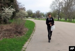 In this May 11, 2018 photo, Emily Mogavero, 17, looks at her cellphone while walking in Delaware Park in Buffalo, N.Y.