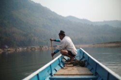 FILE- A local villager drives a boat where the future site of the Luang Prabang dam will be on the Mekong River, on the outskirt of Luang Prabang province, Laos, February 5, 2020. (REUTERS/Panu Wongcha-um)