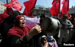 FILE - A Palestinian woman holds a cooking pot during a protest against a U.S. decision to cut funding to the U.N. Relief and Works Agency (UNRWA), outside an aid distribution center, in Khan Younis in the southern Gaza Strip, Sept. 4, 2018.