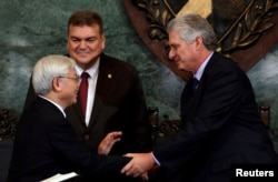 Vietnam's Communist Party Secretary, General Nguyen Phu Trong, shakes hands with Cuba's First Vice-President Miguel Diaz-Canel, next to Gustavo Cobreiro, rector of the University of Havana, in Havana, Cuba, March 29, 2018.