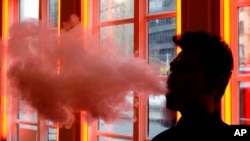 In this Feb. 20, 2014 file photo, a customer exhales vapor from an e-cigarette at a store in New York. (AP Photo)