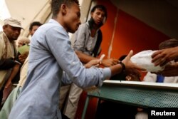 FILE - A man displaced from Yemen's Red Sea city of Hodeidah receives a food ration at a charity food distribution in Sana'a, Yemen, July 3, 2018.