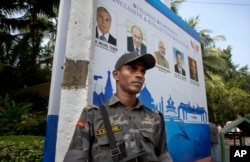 A Goa police commander stands guard near the banner of BRICS summit in Goa, India, Friday, Oct. 14, 2016.