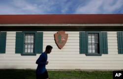 FILE - A man runs past a National Park Service sign in San Francisco, Dec. 22, 2018. A partial federal shutdown has been put in motion because of gridlock in Congress over funding for President Donald Trump's Mexican border wall.