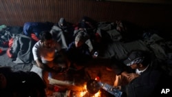 Migrants gather around a fire used for cooking and warmth in an abandoned brick factory in the northern Serbian town of Subotica, Feb. 8, 2017.