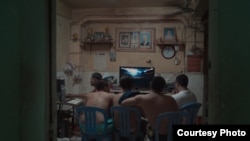 បុរស​មួយ​ក្រុម​កំពុង​មើល​កញ្ចក់​ទូរទស្សន៍ នៅ​ក្នុង​គេហដ្ឋាន​មួយ​នៅ​អគារ​ «ស‍» ឬ​អគារ​ប៊ូឌិញ មុន​ពេល​អគារ​ដ៏​ទ្រុឌទ្រោម​មួយ​នេះ​ត្រូវបាន​វាយ​កម្ទេច​ចោល នៅ​ខែ​កក្កដា ឆ្នាំ​២០១៧។ (រូប​ថត​ផ្តល់​ឲ្យ​ដោយ៖ លោក​នាង កាវិច/Anti-Archive)