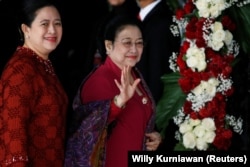 Mantan Presiden Indonesia Megawati Soekarnoputri melambai kepada wartawan saat ia tiba bersama putrinya Puan Maharani, Menteri Koordinator Pembangunan Manusia dan Kebudayaan Indonesia, untuk menghadiri pidato kepresidenan menjelang Hari Kemerdekaan.