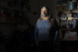In a photo taken Thursday, April 30, 2020, Jane St. Louis, a grocery store employee, poses for The Associated Press in her home's garage in Damascus, Maryland.