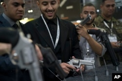 A man tries a revolver displayed at the LAAD Defense and Security International Exhibition in Rio de Janeiro, Brazil, April 2, 2019.