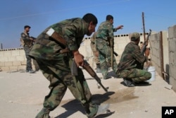 FILE - Syrian soldiers fire return fire, repelling an attack in Achan, Hama province, Syria, Oct. 11, 2015.