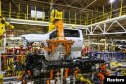 FILE - Robots swing a cab and bed into place for a new heavy duty pickup truck on the assembly line where Chevrolet Silverado trucks are being built at General Motors Flint Assembly in Flint, Michigan, Jan. 30, 2019.