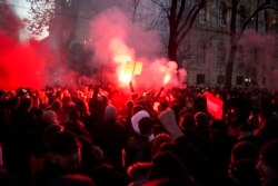 Demonstran meneriakkan slogan-slogan dan suar api selama demonstrasi menentang pembatasan COVID-19 baru di Wina, Austria, 20 November 2021. (Foto: AP)