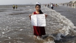 In this Friday, Feb 21, 2020, photo, environmental activist Licypriya Kangujam, 8, holds a sign at Juhu beach during a cleaning drive in Mumbai, India.