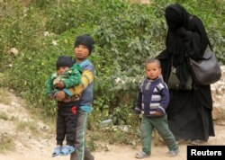 FILE - Woman and children of Islamic state militants walk as they surrendered in the village of Baghouz, Deir Al Zor province, Syria, March 14, 2019.